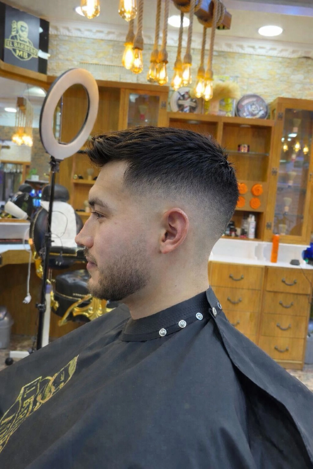 El barbero MB - Haar- und Hautpflegebehandlungen - Seitenansicht eines Mannes mit einem präzisen Skin Fade-Haarschnitt und gepflegtem Bart im Friseursalon.