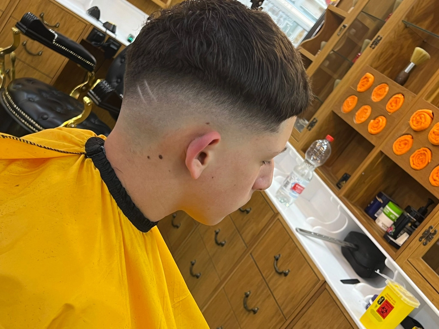 El barbero MB - Haar- und Hautpflegebehandlungen - Seitenansicht eines Jungen mit neuem Haarschnitt im Friseursalon.