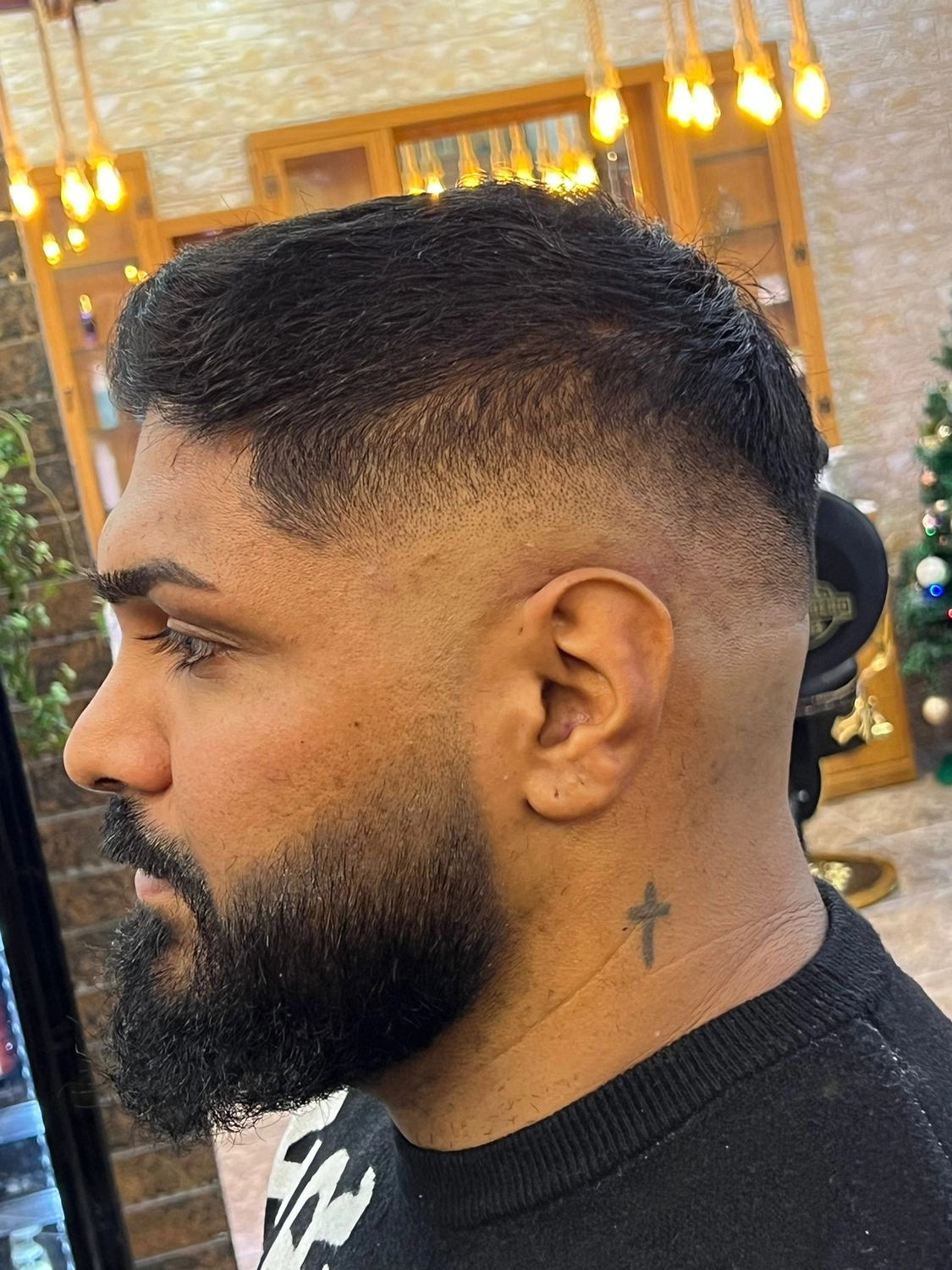 El barbero MB - Haar- und Hautpflegebehandlungen - Seitenansicht eines Mannes mit einem präzisen Skin Fade-Haarschnitt und gepflegtem Bart im Friseursalon.
